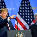 Bolton’s Guilty Plea Stuns D.C. Two men at a press conference with U.S. flags behind them