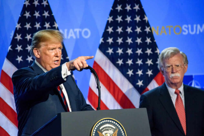 Two men at a press conference with U.S. flags behind them