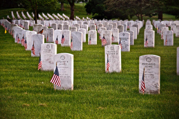 Rows of white headstones with American flags in a military cemetery