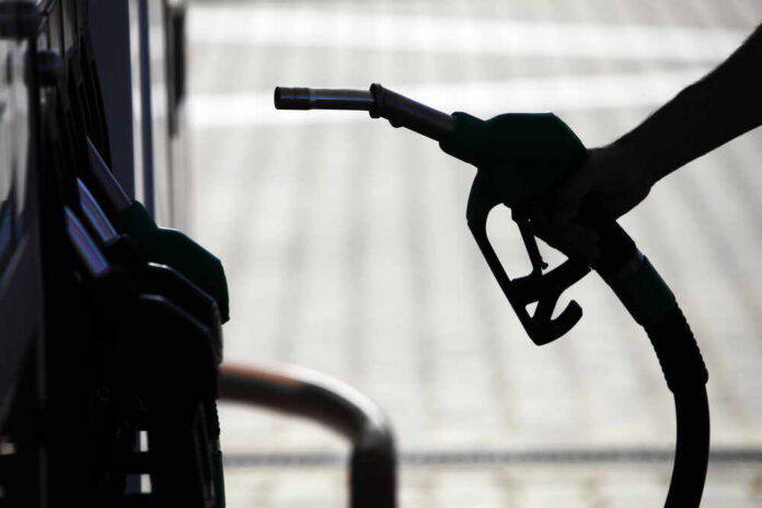 Detail,Of,A,Hand,Holding,A,Fuel,Pump,At,A Silhouette of a hand holding a fuel nozzle at a gas station