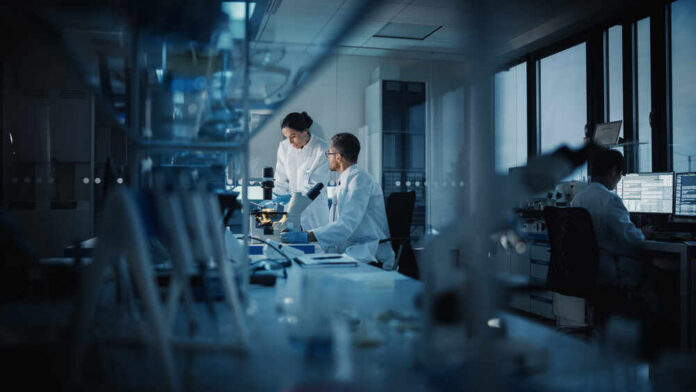 Modern,Medical,Research,Laboratory:,Two,Scientists,Working,,Using,Digital,Tablet, Two scientists working in a laboratory with a microscope and computer screens