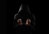 Convicted Teen’s Haunting Line Caught On Tape A hooded figure with hands in handcuffs against a dark background
