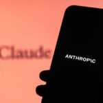 Hacking Superweapon Goes Public—With a Catch A hand holding a smartphone displaying the word 'ANTHROPIC' against a blurred background