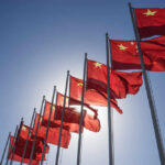 Multiple Chinese flags waving against a clear blue sky