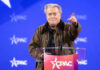 Bannon Blasts Mullin Over Bovino Comment Person speaking at CPAC conference blue background