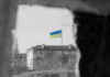Ukrainian flag over apartment building seen through a dark frame