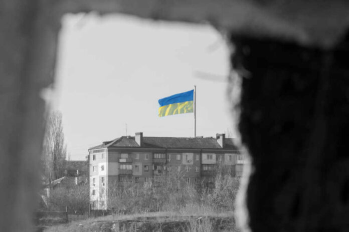 Ukrainian flag over apartment building seen through a dark frame