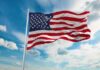 Patriotism Branded Dangerous — Backlash Erupts American flag waving on a flagpole against a blue sky with clouds