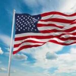 Patriotism Branded Dangerous — Backlash Erupts American flag waving on a flagpole against a blue sky with clouds