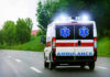 Tree Job Turns Nightmare in Oklahoma Ambulance driving on a road with flashing lights.