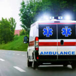 Tree Job Turns Nightmare in Oklahoma Ambulance driving on a road with flashing lights.
