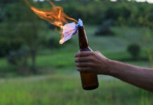 hand holding a glass bottle with a burning rag