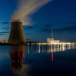 Cooling tower of a power plant at night beside a calm river