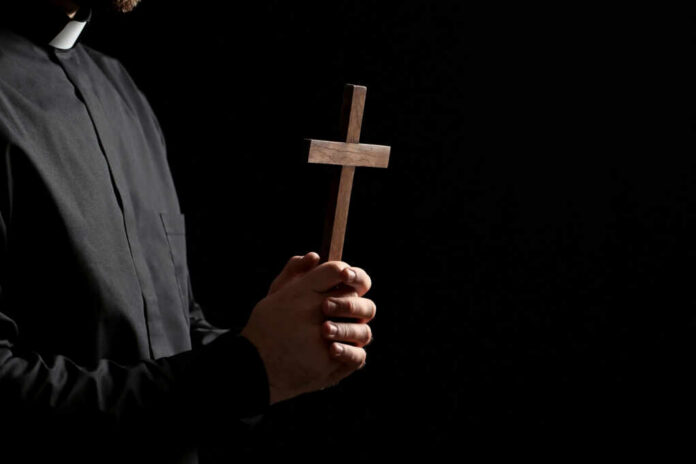 Clergyperson holding a wooden cross
