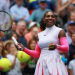 Tennis player smiling holding racket on court