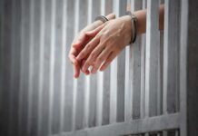 Registry Roundup Nails Town Manager Hopeful handcuffed hands resting through prison bars
