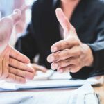 Entrepreneur Explosion Stuns America Two people extending hands for a handshake across a desk
