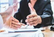 Entrepreneur Explosion Stuns America Two people extending hands for a handshake across a desk