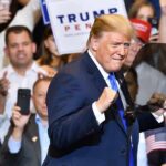 Trumpism Invades Europe — Brussels Rattled man in suit raising fists at a rally podium