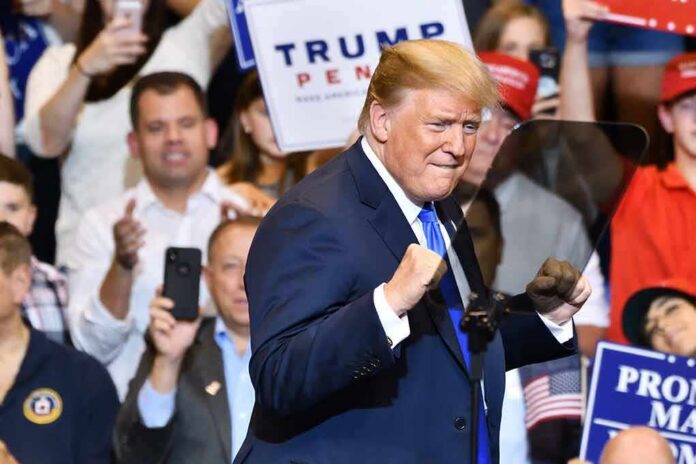 man in suit raising fists at a rally podium