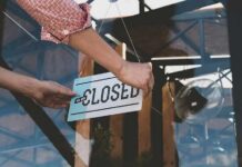 Hands hanging a closed sign on a glass door