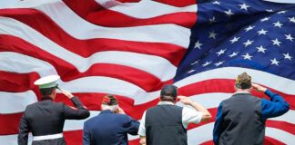 Veterans salute a large American flag