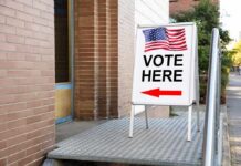 Election ‘Rigging’ Charge Rocks Prop 39 Sidewalk sign with American flag directing to a polling place