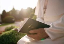 Who Really Picks China’s Bishops? Person in white robe holding a Bible outdoors