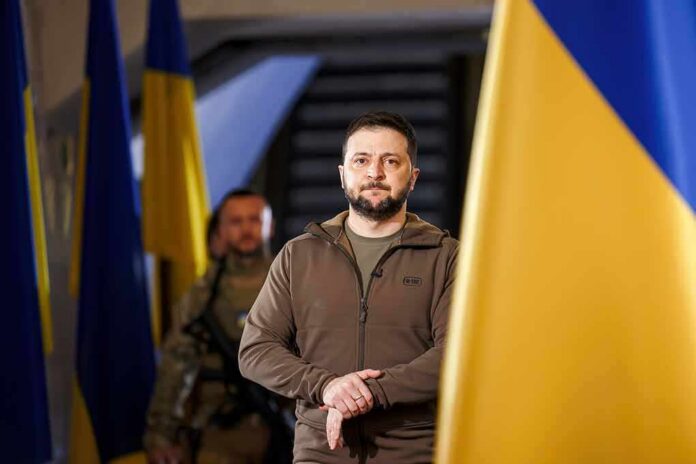 man in olive jacket standing between large blue and yellow flags