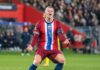 Soccer player in Norway kit shouting with arms outstretched