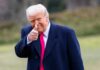 Trump’s Swag Room Raises Eyebrows A man in a dark coat and pink tie giving a thumbs up outdoors