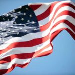 Kindness Overload Stuns World Cup Traveler Waving American flag against a clear blue sky