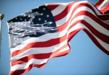 Kindness Overload Stuns World Cup Traveler Waving American flag against a clear blue sky