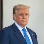 Communist Menace? Trump Draws a Hard Line A political figure standing outdoors with a serious expression