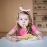 Girl eating spaghetti at a table