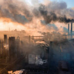 Industrial facility with smoking chimneys under a colorful sky