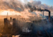 Industrial facility with smoking chimneys under a colorful sky