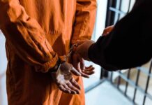 Prisoner in orange jumpsuit handcuffed by officer