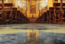 Church interior with wooden pews facing ornate altar