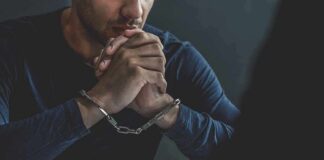 man in handcuffs resting clasped hands on table