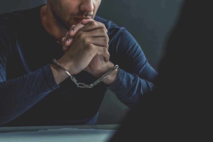 man in handcuffs resting clasped hands on table