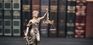 Lady Justice statue with scales in front of law books