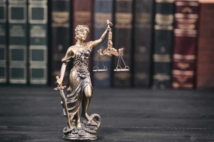 Lady Justice statue with scales in front of law books