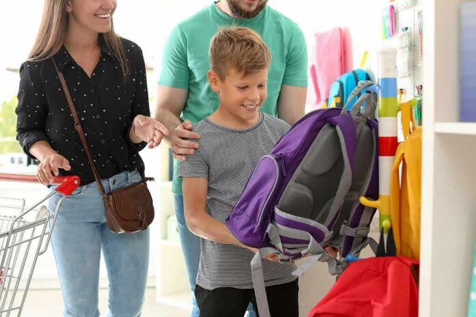 shutterstock_1163223340 Boy choosing a purple backpack in a store with adults nearby