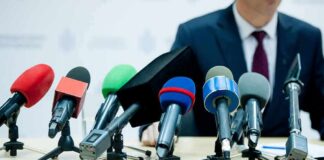 microphones clustered on a table at a press conference