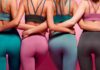 Four women in colorful activewear standing arm in arm