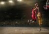 Two basketball players contest a layup under the hoop