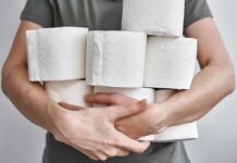Trade Crossfire Targets Daily Essentials – TP Takes The Hit Person holding multiple toilet paper rolls