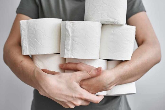 shutterstock_1674320413 Person holding multiple toilet paper rolls