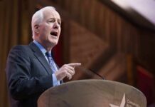 Defection Stings—Talarico Nabs Cornyn Insider Elderly man in suit speaking at a podium